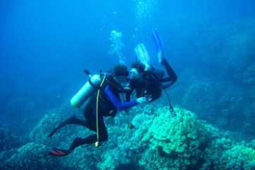 Two divers helping each other underwater