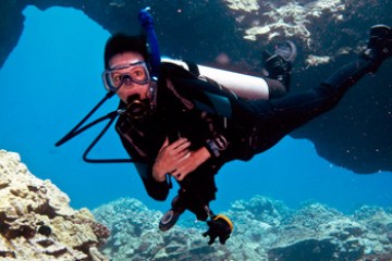 Diver swimming through coral reefs in Hawaii